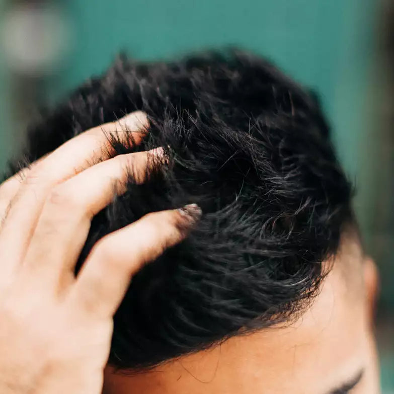 Mano pasando por el pelo oscuro de un hombre peinado con O'DOUDS Dry Wax
