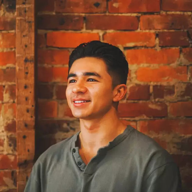 Hombre joven sonriendo ante una pared de ladrillo, peinado con SHEAR REVIVAL Northern Lights