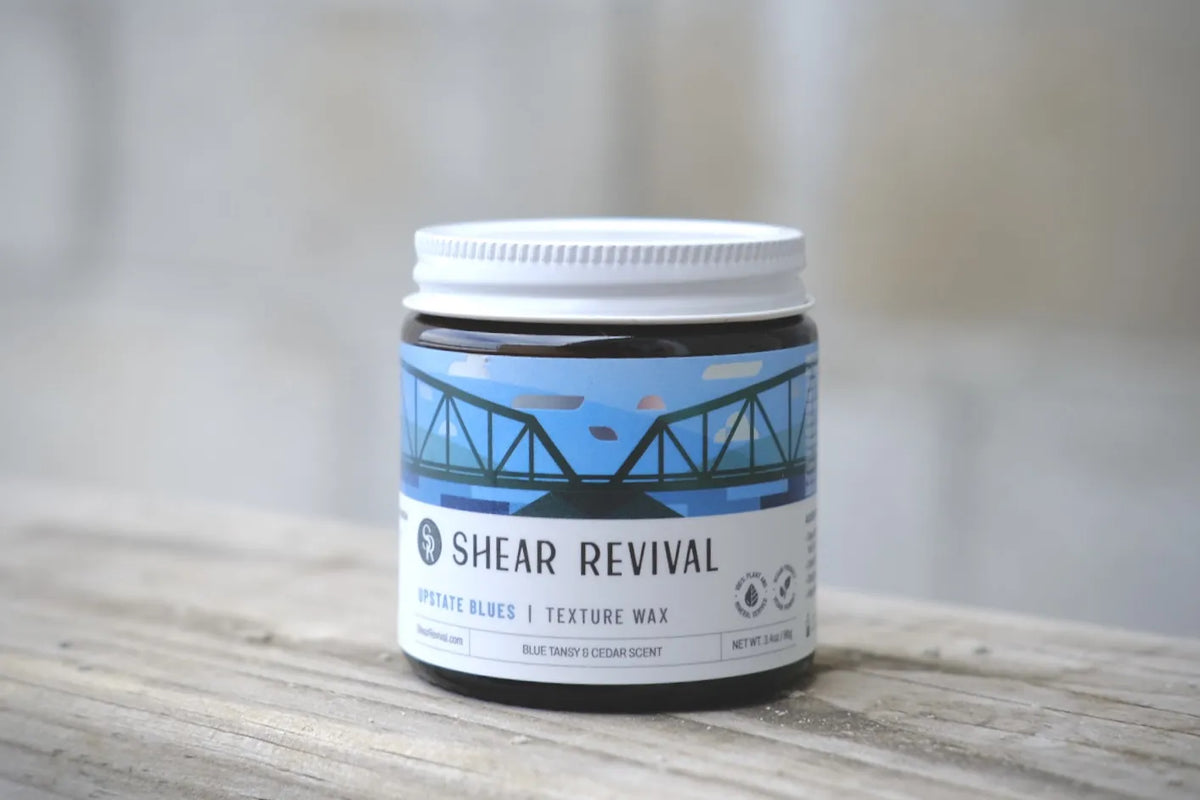 Tarro de SHEAR REVIVAL Upstate Blues Texture Wax sobre una mesa de madera