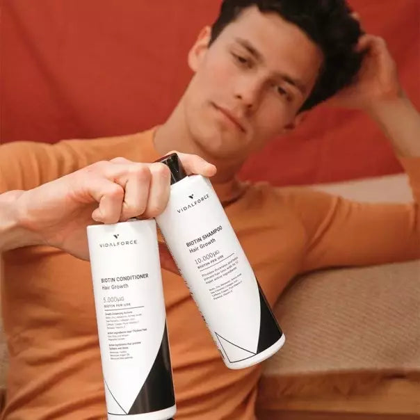 Hombre recostado con dos botellas de la gama de biotina de VIDALFORCE