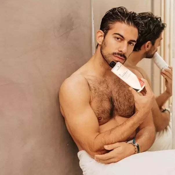 Hombre apoyado en la pared con la botella de VIDALFORCE champú 2