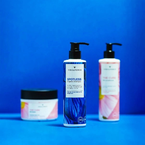 VIDALFORCE SPOTLESS champú, tarro y botella de THE CURE sobre fondo azul