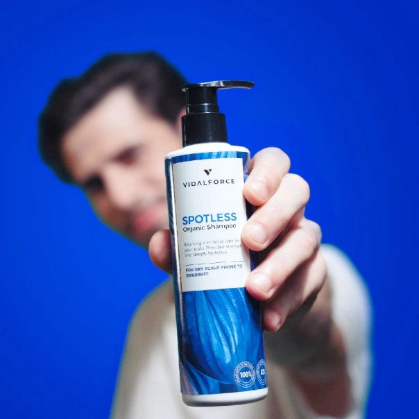 Hombre desenfocado sosteniendo la botella de VIDALFORCE SPOTLESS champú