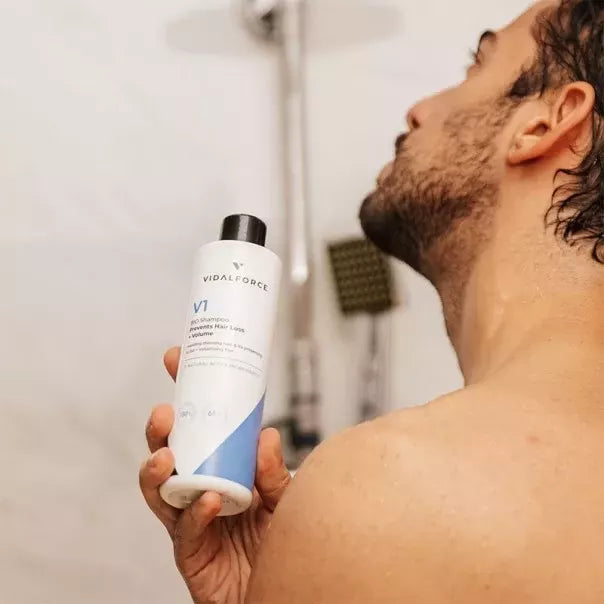 Hombre en la ducha con la botella de VIDALFORCE champú V1