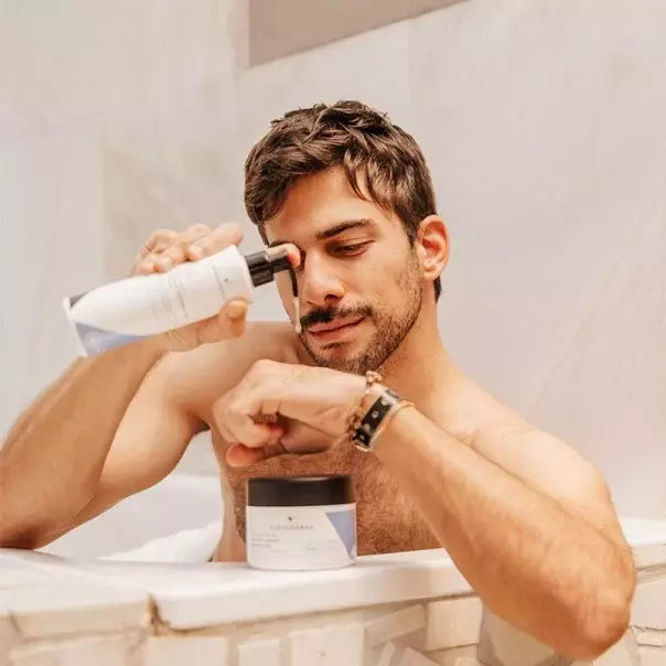 Hombre mostrando la botella de VIDALFORCE champú V1 junto a su ojo