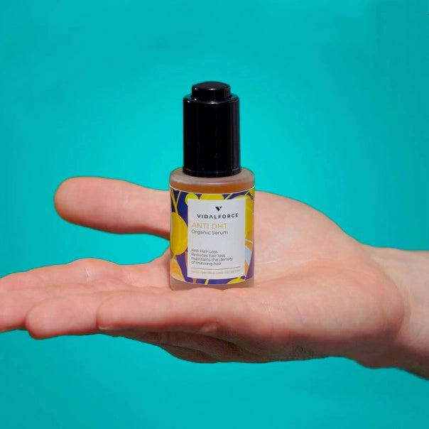 Frasco de VIDALFORCE serum Anti DHT sobre la palma de una mano, fondo turquesa
