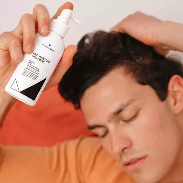 Hombre con los ojos cerrados sosteniendo el spray de VIDALFORCE tónico tratamiento