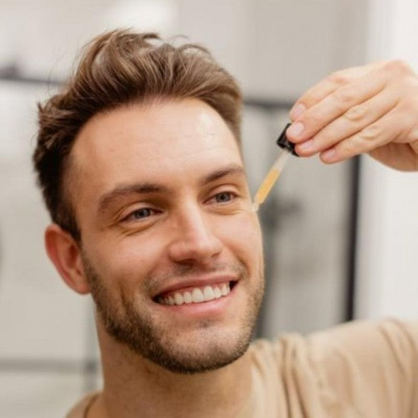 Hombre sonriendo con el cuentagotas de WIDES FOREST sérum facial junto a la cara