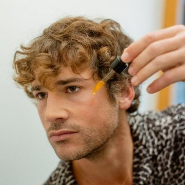 Hombre de pelo rizado aplicándose WIDES FOREST sérum facial