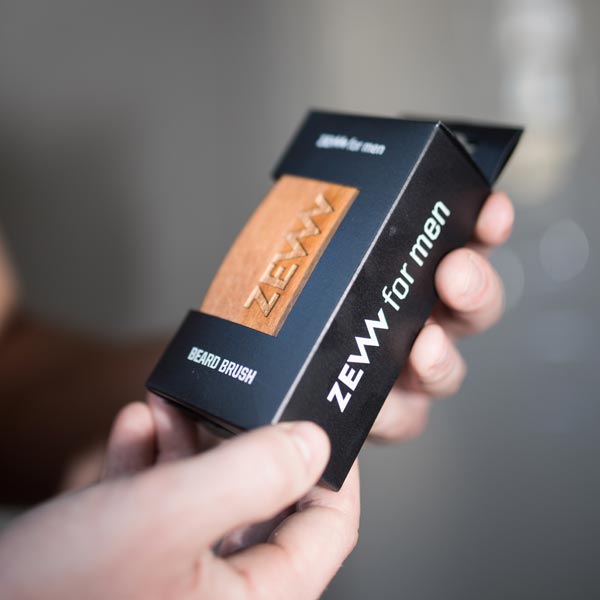 Manos sosteniendo la caja del cepillo ZEW Beard Brush