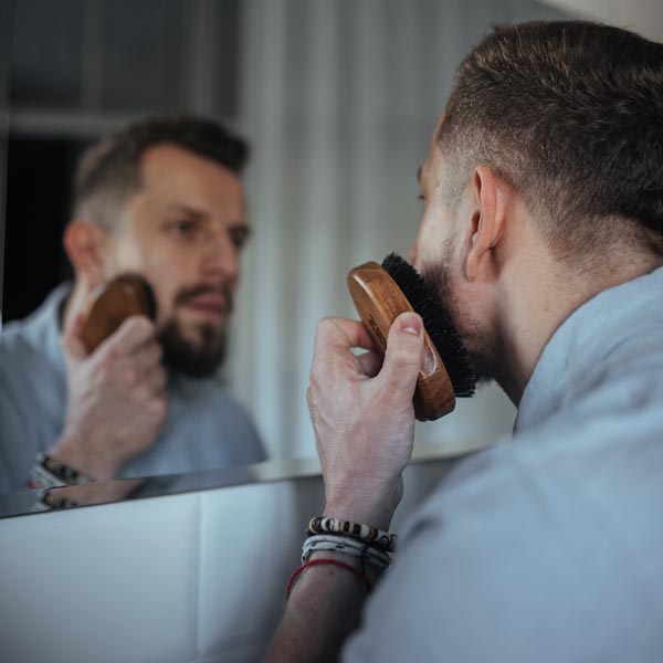 Hombre cepillándose la barba con ZEW Beard Brush frente al espejo