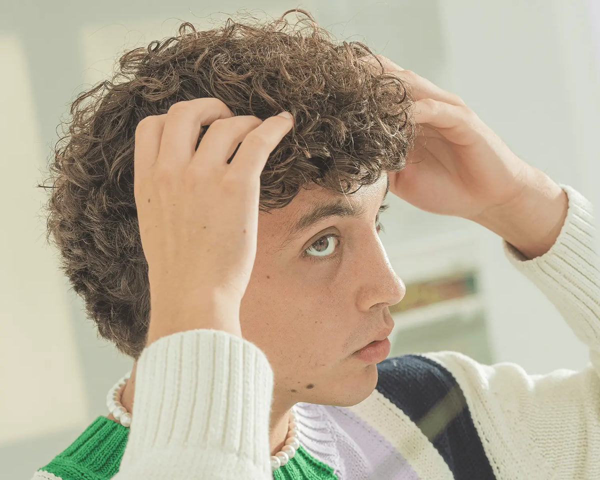 Hombre con pelo rizado peinándose con crema BY ELEMENTUM Montibus